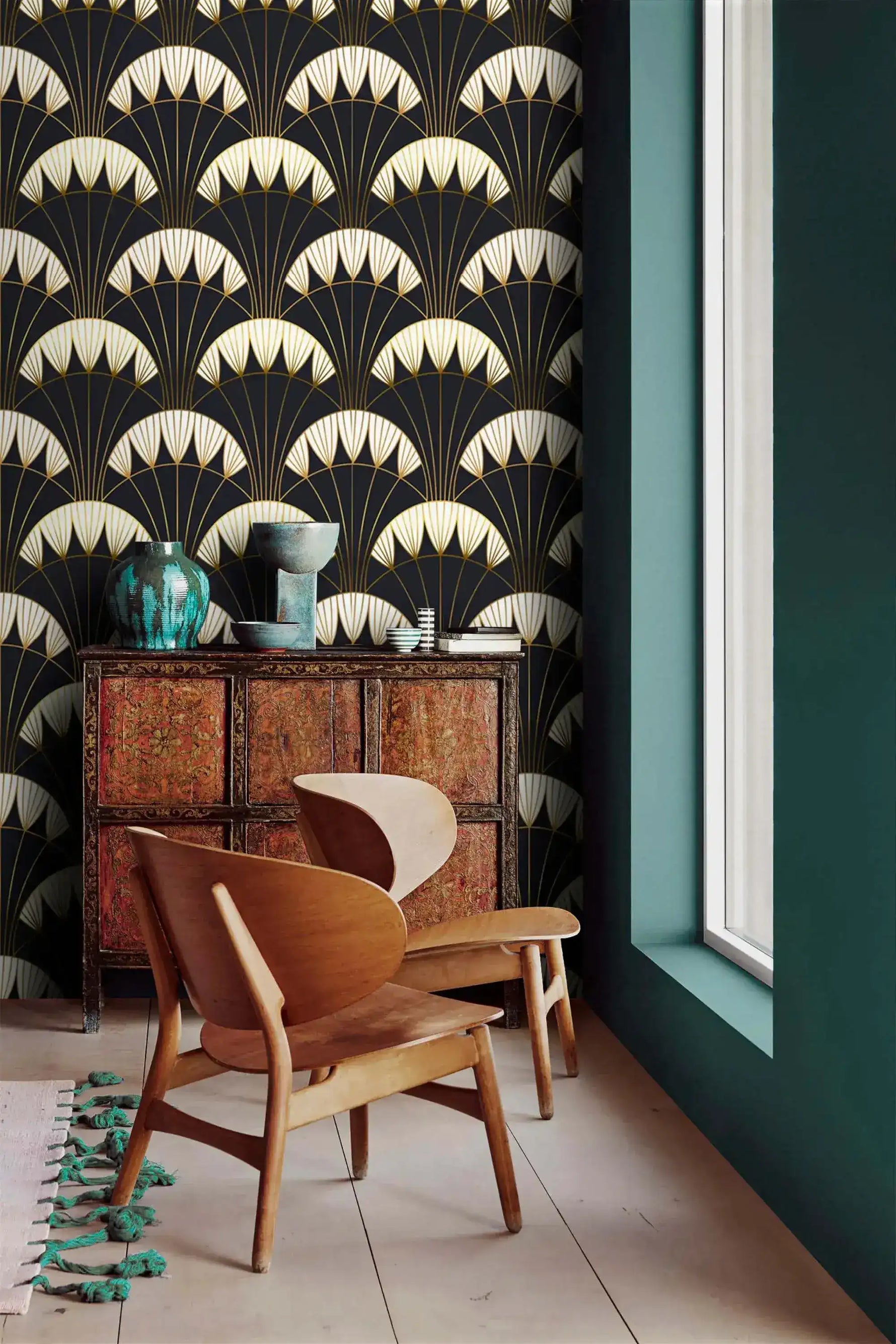 Art Deco black gold wallpaper styled in a room with wood lounge chair, vintage chest, teal vase, fan-scallop pattern