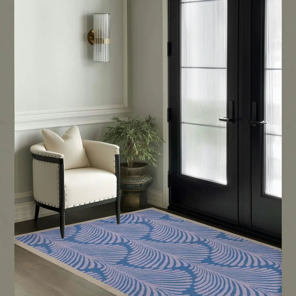 A stylish Art Deco Scallop Blue hand-tufted wool rug graces the floor of a modern, well-lit office setting. The large area rug features an elegant blue and white scallop design, complementing the sophisticated white armchair and potted plant nearby. Perfect for enhancing large living rooms or office spaces, this wool rug adds a touch of luxury and comfort.