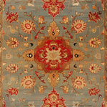Artisan Floral Masterpiece rug close-up texture; grey-blue wool pile with red medallion and golden-tan scrolling floral vines, fine knotted detail