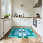 A stylish Aztec Blue hand-tufted wool area rug adds a splash of color to a modern kitchen setting. The geometric design complements the wooden floor, making it a perfect choice for dining rooms and bedrooms alike.