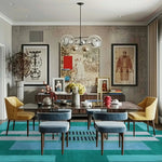 A stylish dining room featuring an Aztec Blue Hand Tufted Wool Rug. The area rug, with its vibrant blue hue and modern geometric patterns, adds a touch of elegance to the space. Perfect for dining room carpets, this wool rug complements the contemporary decor, featuring a sleek dining table and colorful chairs.