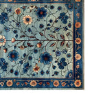 Top view of the Azure Eternal Knotted Wool Area Rug, showcasing an intricate floral pattern with rich blue and peach tones, surrounded by a detailed border.