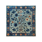 The Azure Eternal Knotted Wool Rug features an intricate floral design with vibrant blue and beige blossoms on a soft blue background, bordered by a detailed floral pattern. This exquisite area rug adds a touch of elegance and sophistication to any room.