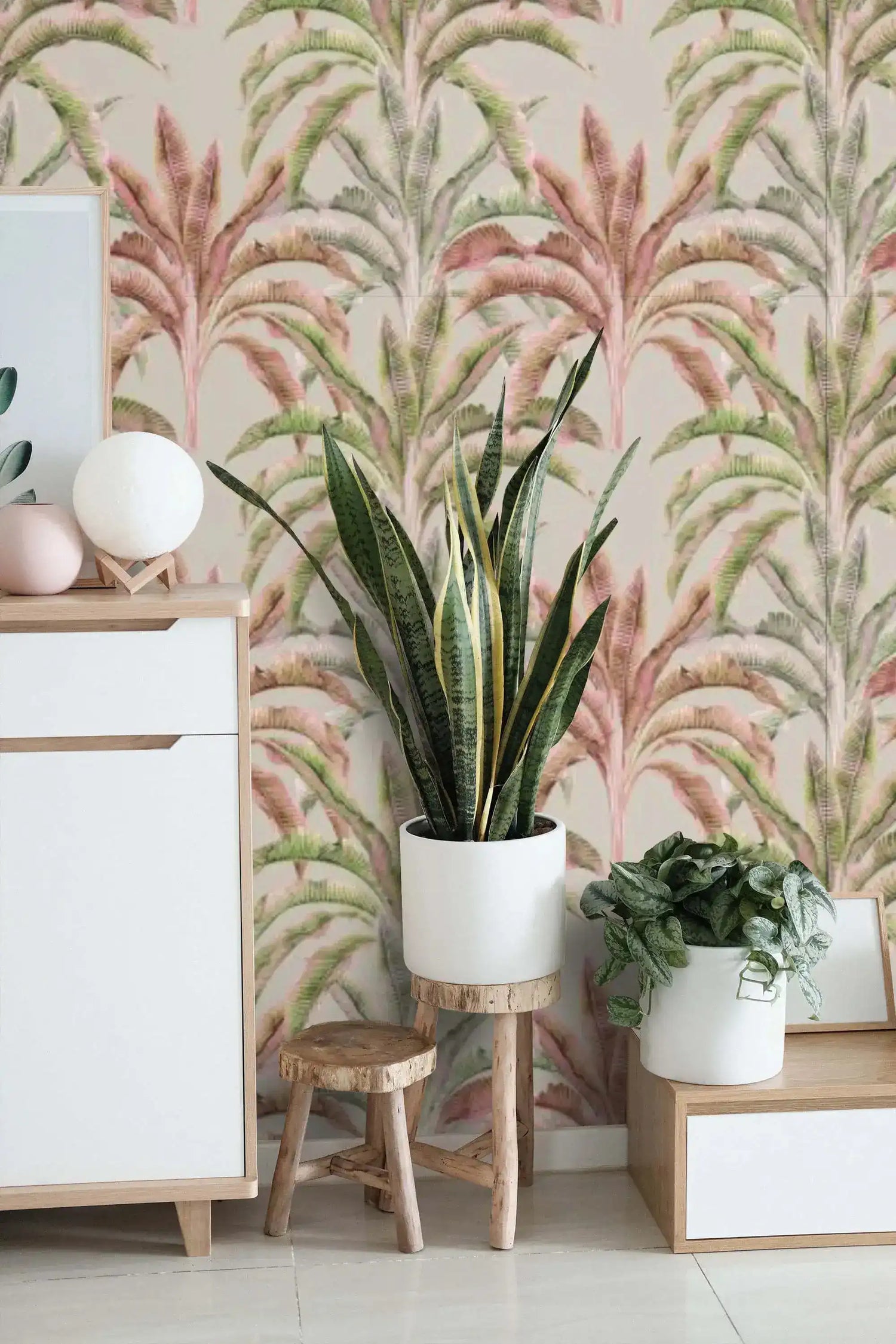 Banana grove wallpaper in pink and green leaf print behind a styled console with potted plants