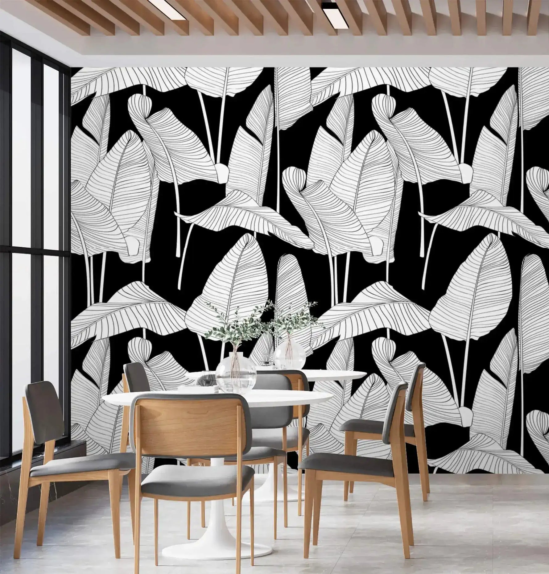 Oversized banana leaf wallpaper on black covering a full wall behind a white oval dining table and wood-framed chairs