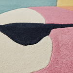 Close-up of a colorful geometric rug with pink, blue, and black shapes.