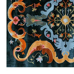 A vibrant and intricately designed area rug featuring bold baroque patterns with swirling orange, pink, blue, and gold motifs on a dark background, showcasing the craftsmanship and elegance of hand-tufted wool.