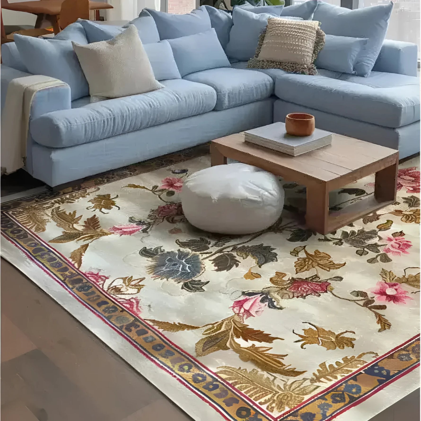A beautifully designed Golden Glory Square Hand Tufted Wool Rug graces the floor of a cozy living room. The square area rug features an elegant floral pattern with vibrant colors, making it a perfect choice for bedrooms or large living rooms. The wool rug complements the light blue sectional sofa, creating a warm and inviting atmosphere, ideal for area rugs in living rooms.