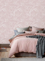 Bed with pink and grey linens against pink floral sketch wallpaper of white line blossoms