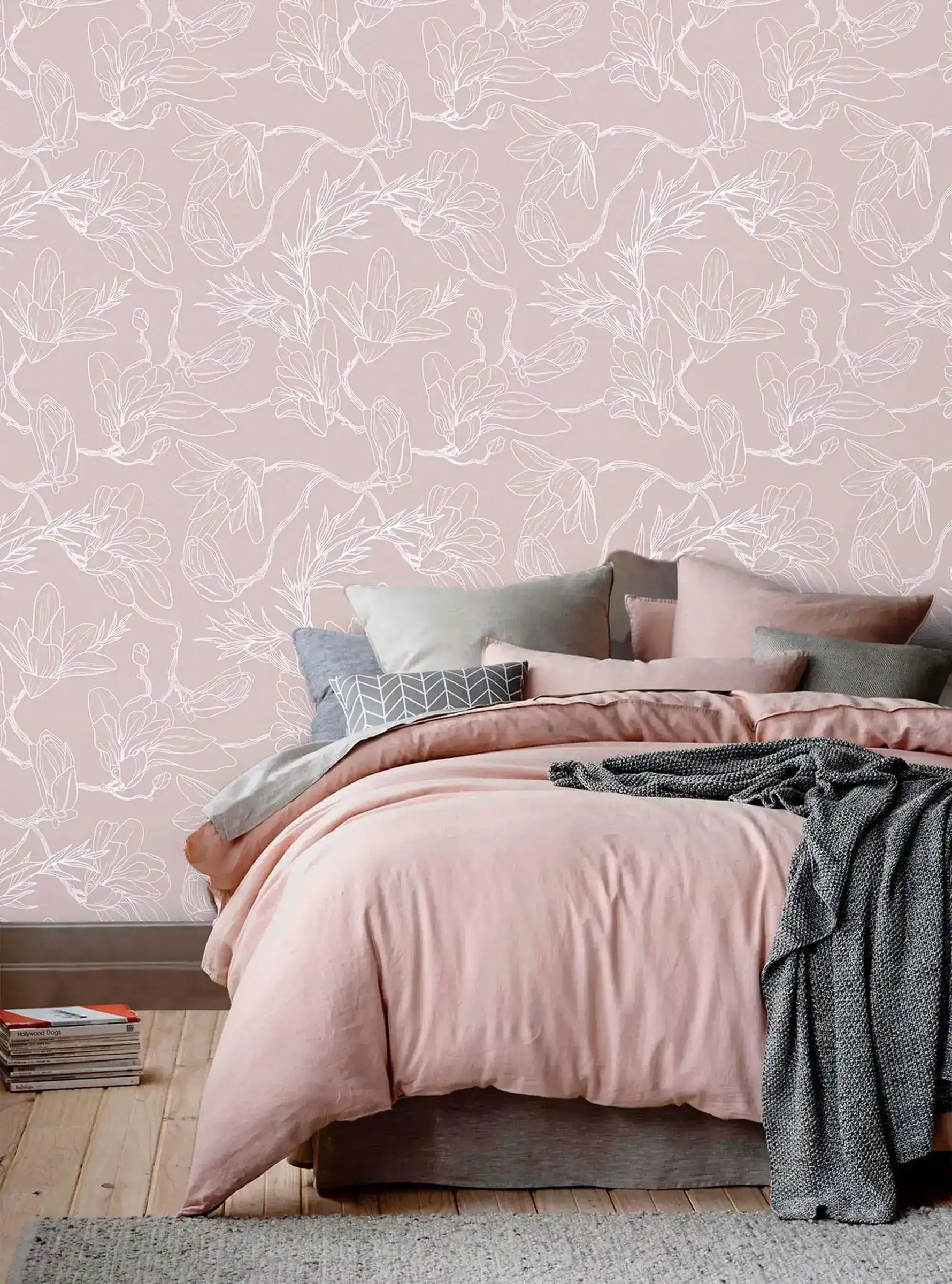 Bed with pink and grey linens against pink floral sketch wallpaper of white line blossoms