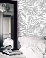 Bedroom with Grey Tropical Foliage Wallpaper, white bedding and black-framed mirror
