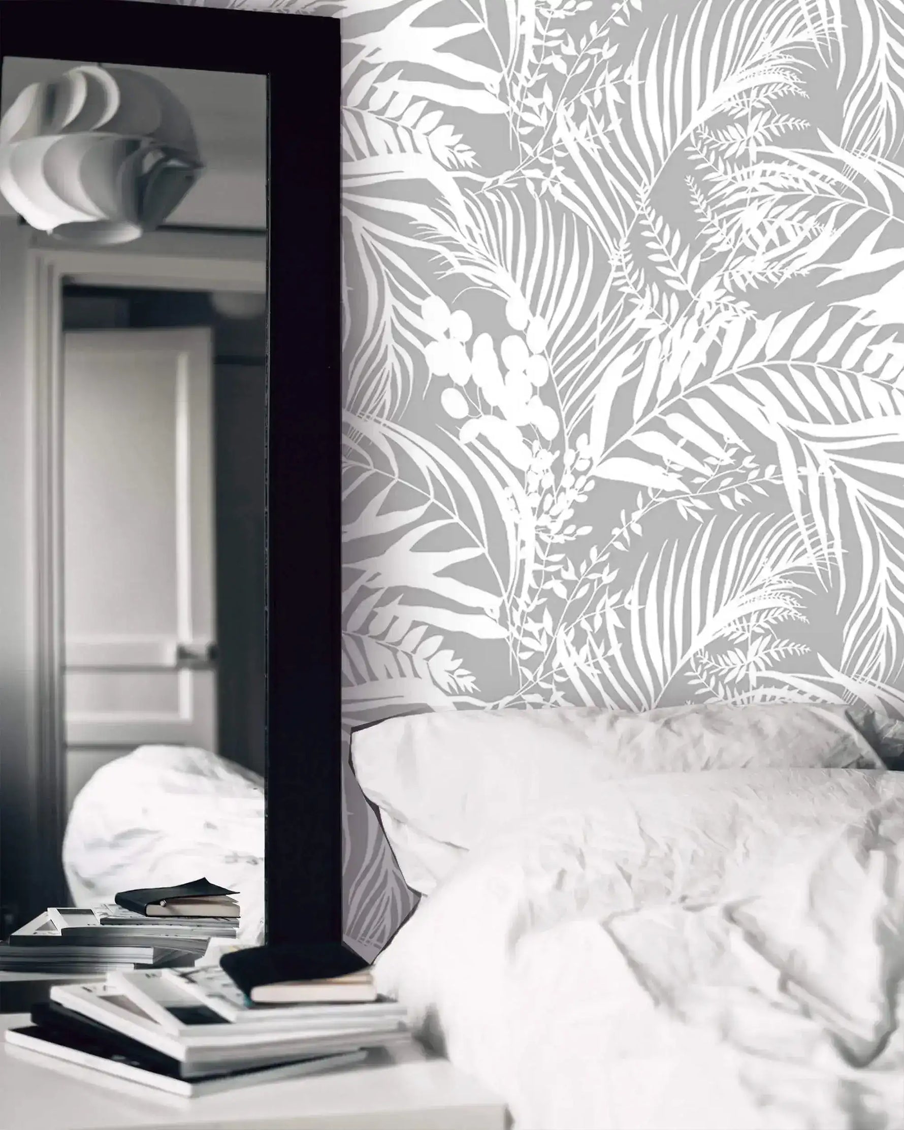 Bedroom with Grey Tropical Foliage Wallpaper, white bedding and black-framed mirror