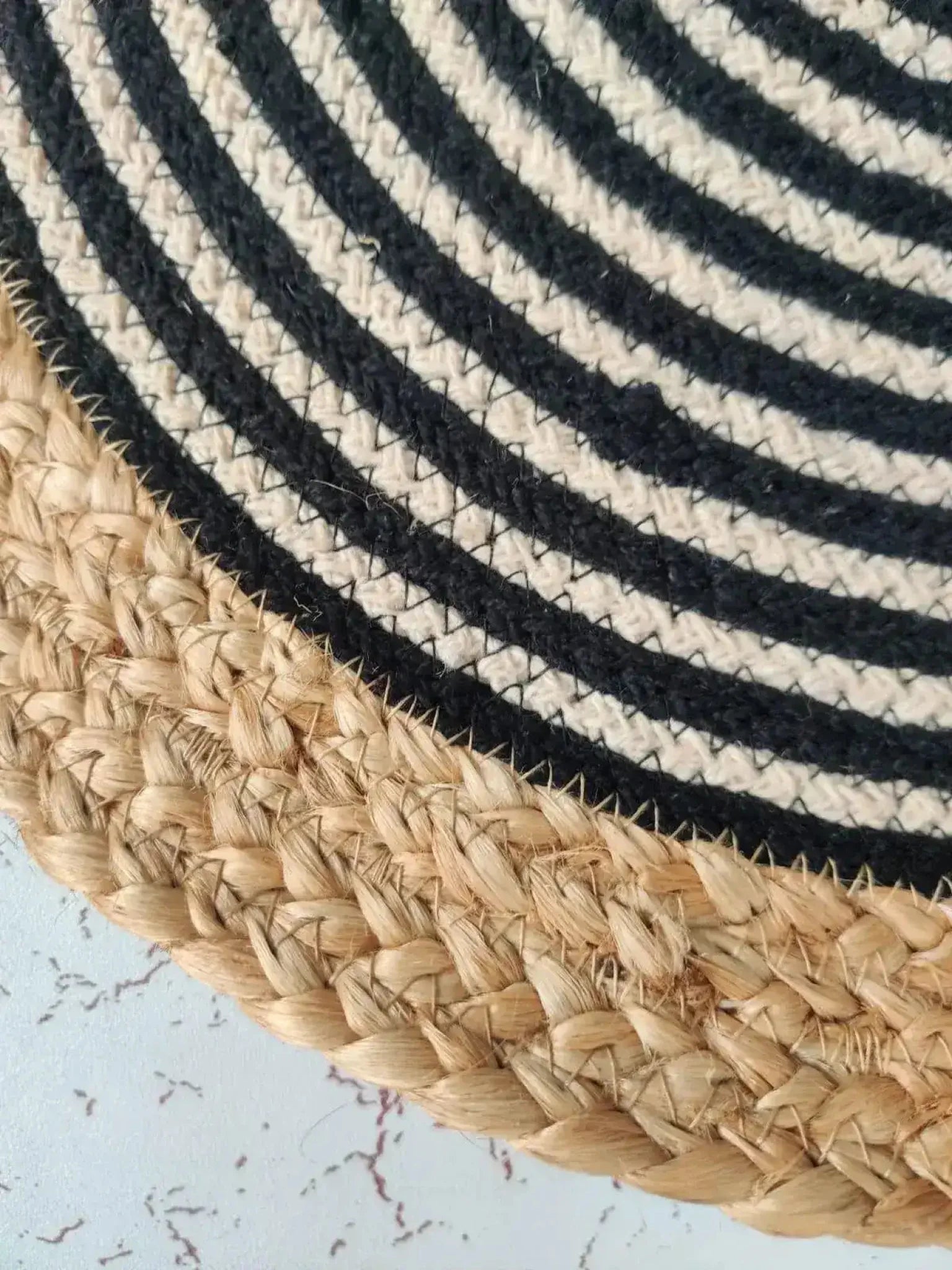 Close-up of a Beige and Black Oval Jute Rug, showcasing its intricate woven pattern. This stylish area rug is perfect for adding a natural touch to your living room, bedroom, or as a bathroom runner rug. The durable jute material makes it ideal for kitchen rugs and hallway runner rugs, offering both elegance and functionality.