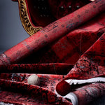 Luxurious hand-knotted wool area rug in rich red hues, displaying intricate patterns with elegant gold detailing, paired with a classic chair for an opulent touch.