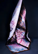 Elegant hand-knotted wool area rug displayed in a dramatic fold against a dark backdrop. The rug features a vibrant mix of colors including reds, blues, and browns, showcasing its intricate design and texture.