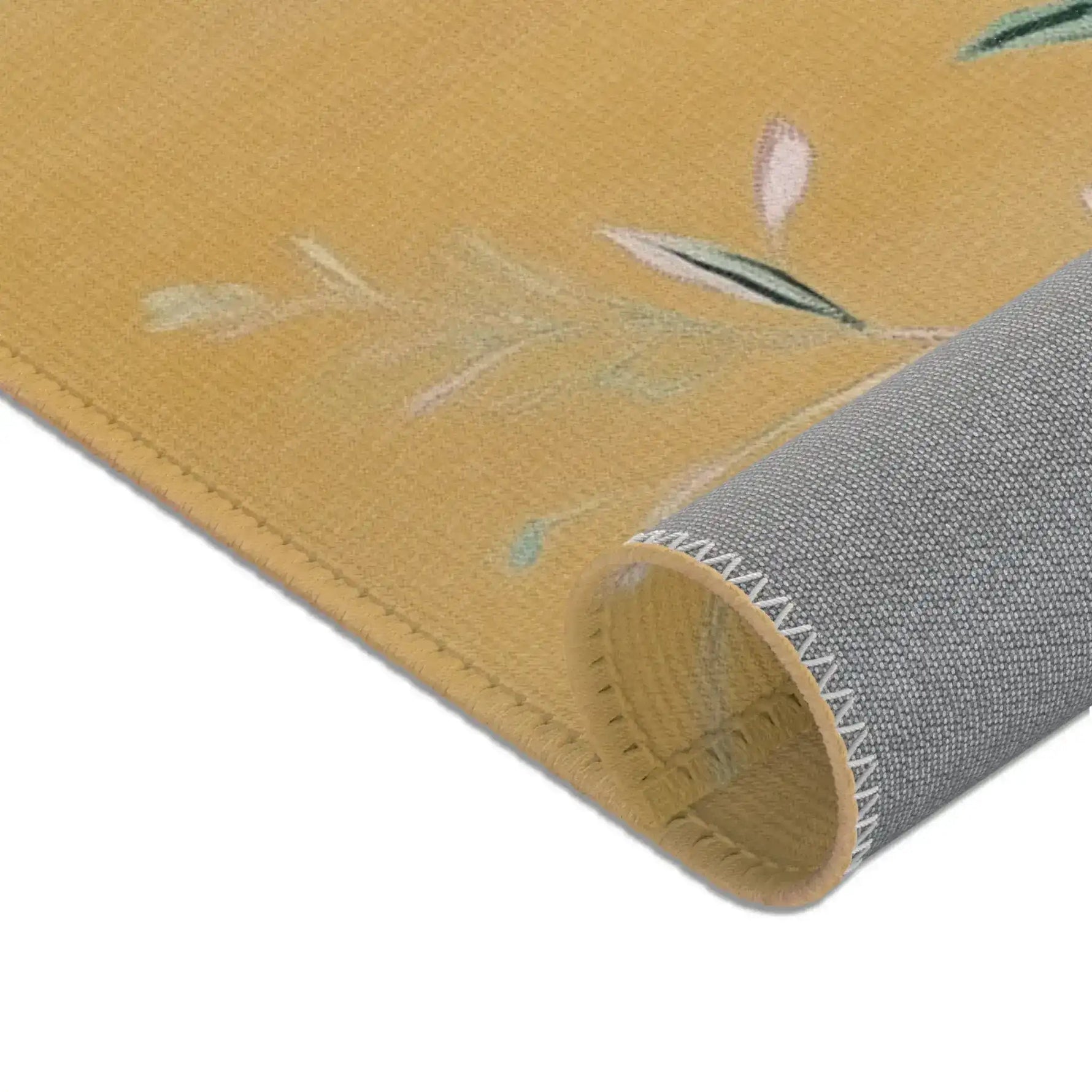 Lower corner roll of Birds and Blossoms Accent Rug showing grey backing, stitched zigzag hem on golden ochre floral rug face