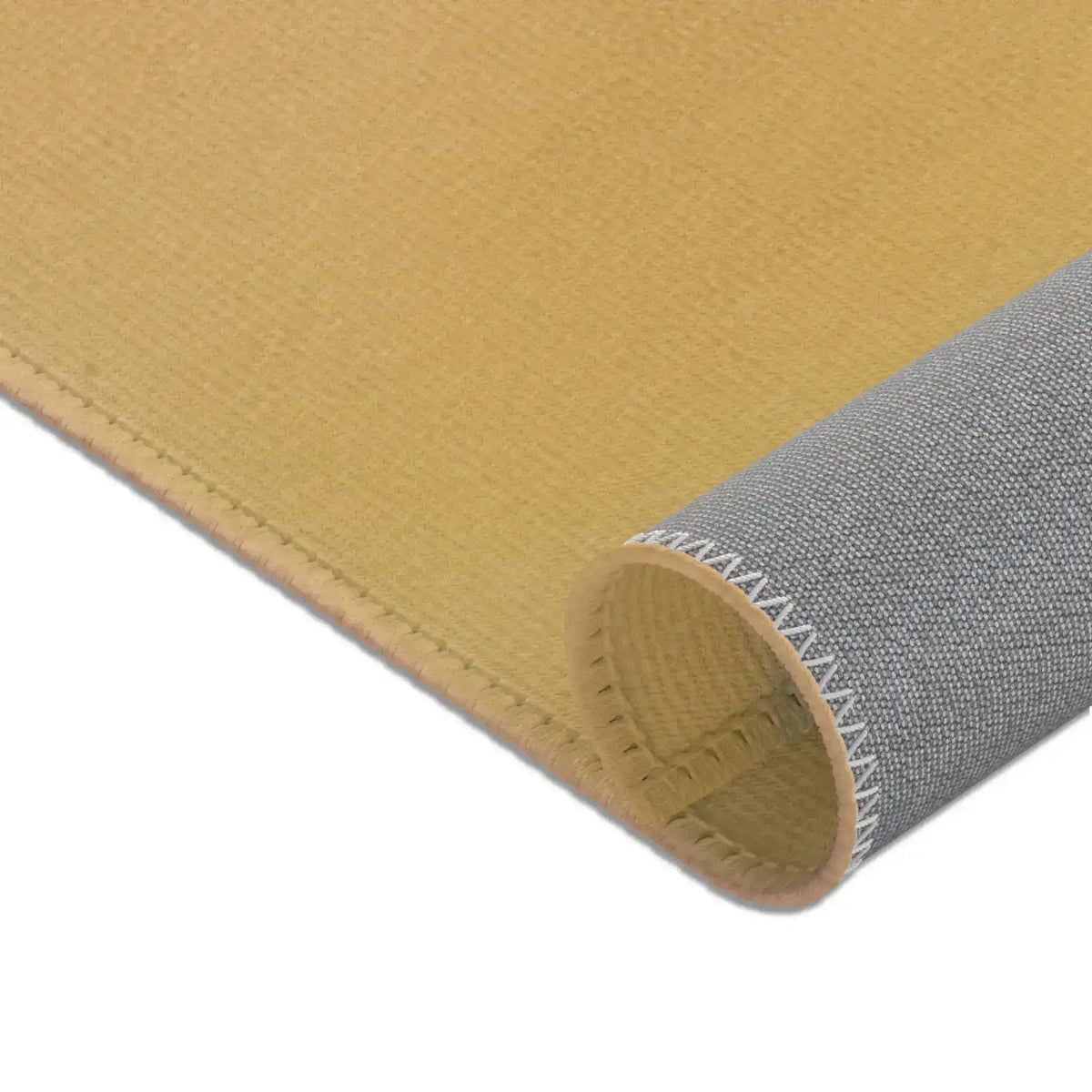 Rolled corner of Birds and Blossoms Accent Rug showing plain golden ochre woven face and grey non-slip fabric backing