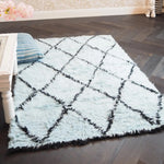 A cozy Black and Blue Diamonds Shag Wool Rug is elegantly placed in a stylish living room. This area rug, perfect for living room spaces, features a plush texture and a modern design with intersecting black lines on a soft blue background. Ideal for those seeking luxurious wool rugs for their living room decor.