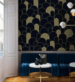 Black and gold art deco arch wallpaper above a blue velvet banquette with marble bistro tables