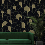 Black and gold art deco arch wallpaper behind an emerald sofa with a potted palm