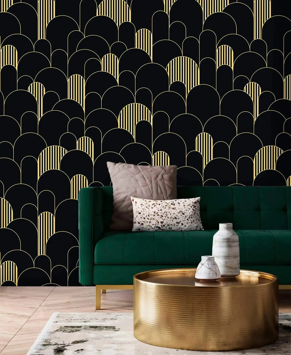 Black and gold art deco arch wallpaper behind an emerald velvet sofa with brass drum coffee table