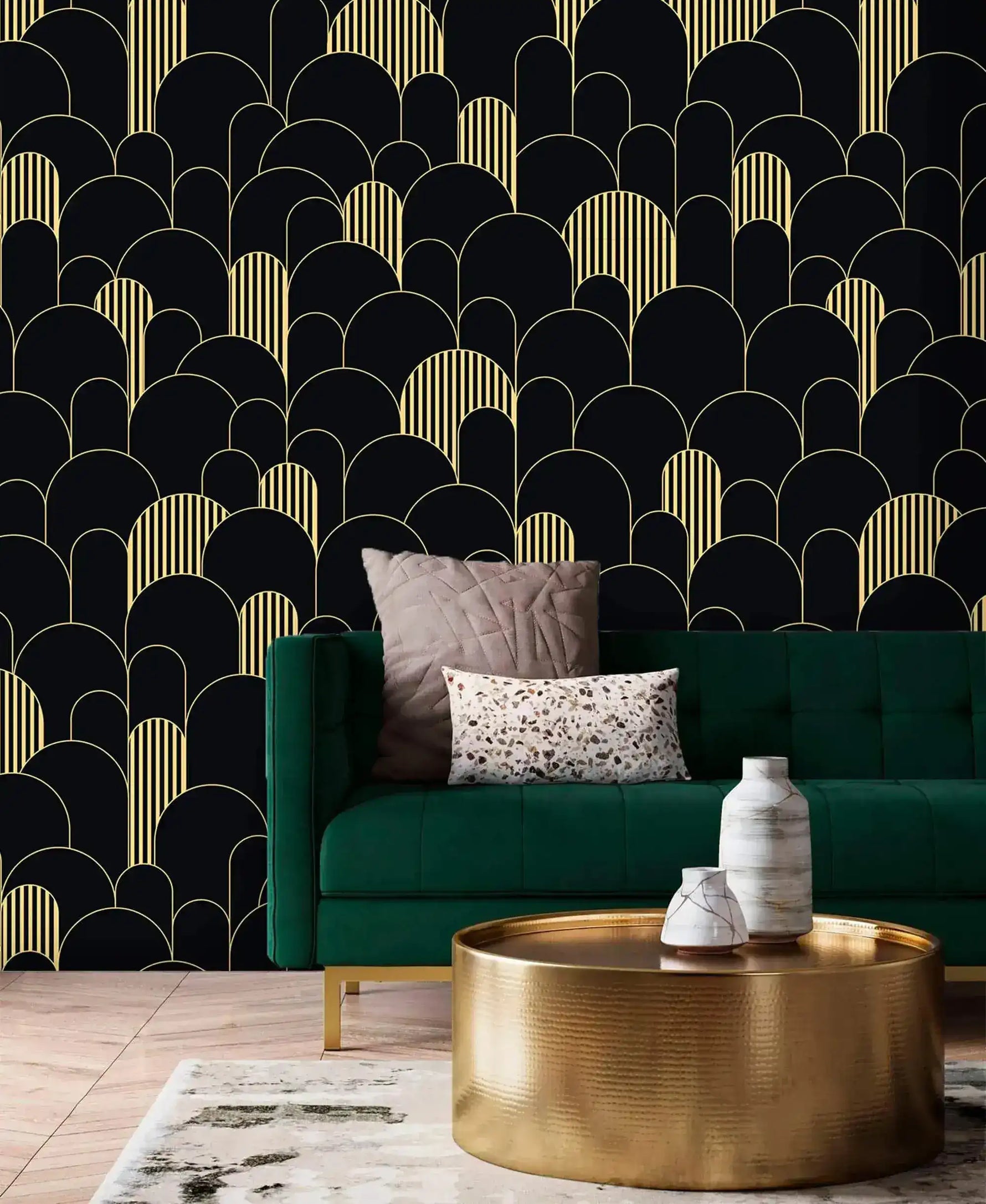 Black and gold art deco arch wallpaper behind an emerald velvet sofa with brass drum coffee table