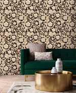 Black and gold damask floral wallpaper behind emerald green velvet sofa and brass coffee table