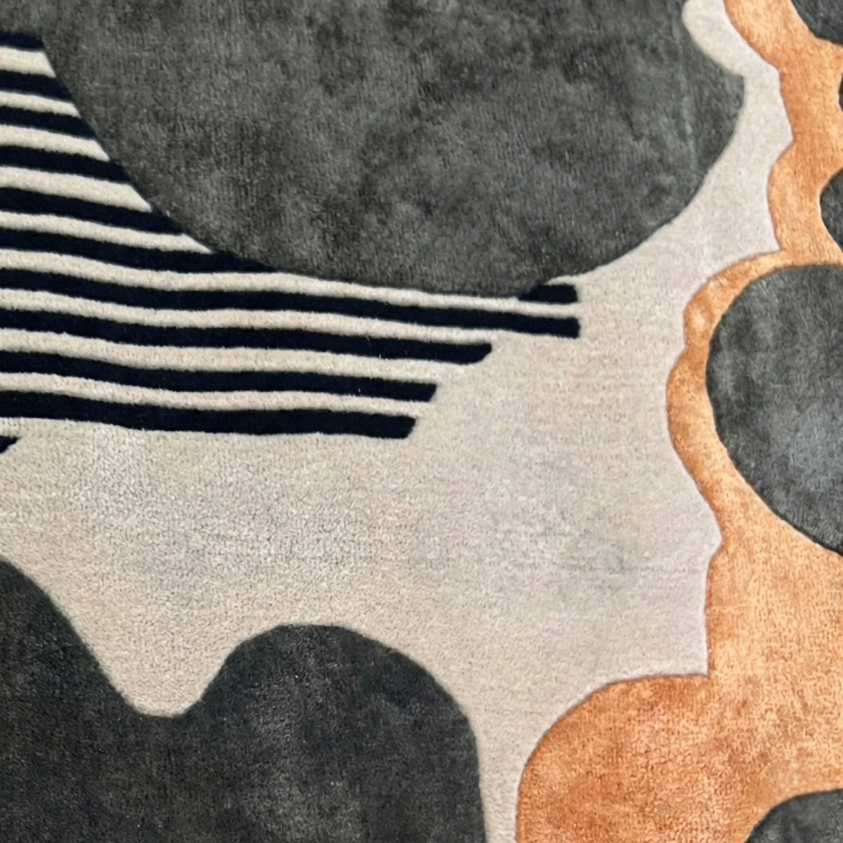 Close‑up of black and gold striped hand‑tufted wool rug showing detailed fiber texture and alternating stripe pattern