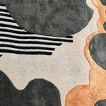 Close‑up of black and gold striped hand‑tufted wool rug showing detailed fiber texture and alternating stripe pattern