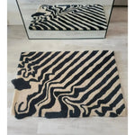 A stylish black and tan melting hand-tufted wool area rug with an abstract pattern, ideal for dining rooms. This large area rug, seen in a top-down view, adds a vintage touch and complements dining room carpets with its unique design.
