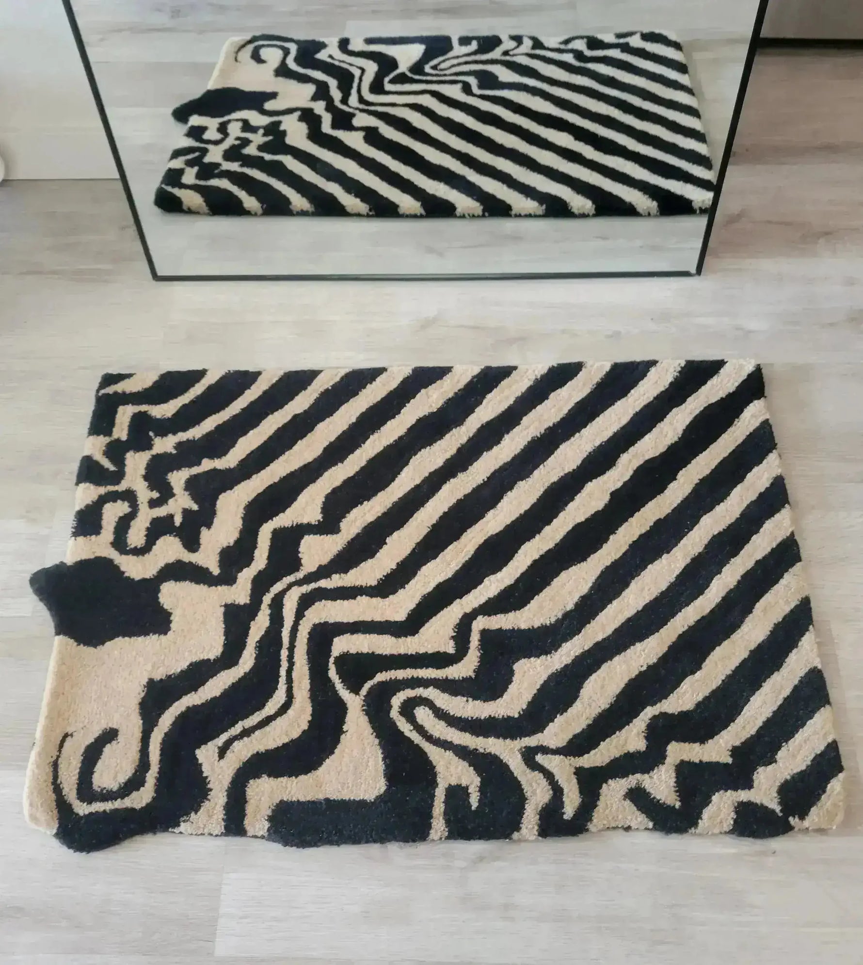 A stylish black and tan melting hand-tufted wool area rug with an abstract pattern, ideal for dining rooms. This large area rug, seen in a top-down view, adds a vintage touch and complements dining room carpets with its unique design.