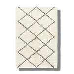 Top view of a black and white minimalist shaggy hand woven wool area rug featuring a geometric diamond pattern. Ideal for use as a bathroom runner rug, kitchen rug, bedroom rug, or hallway runner, adding a cozy touch to any space.