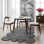 Dining room with a round table and chairs on a black and white jute rug.
