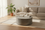 Black and white striped mother of pearl inlay round coffee table in a neutral living room with a cream sofa.