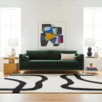 Modern living room with a green sofa, abstract white and black rug, and decorative items.
