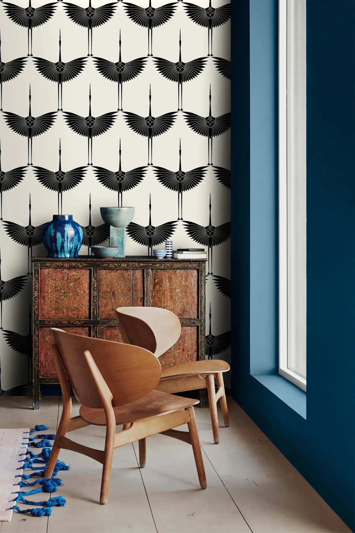 Black Heron crane silhouette wallpaper beside a navy wall with antique cabinet and chair