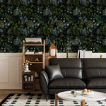 Black leather sofa and shelf against enigmatic leafy canopy wallpaper above white panelling