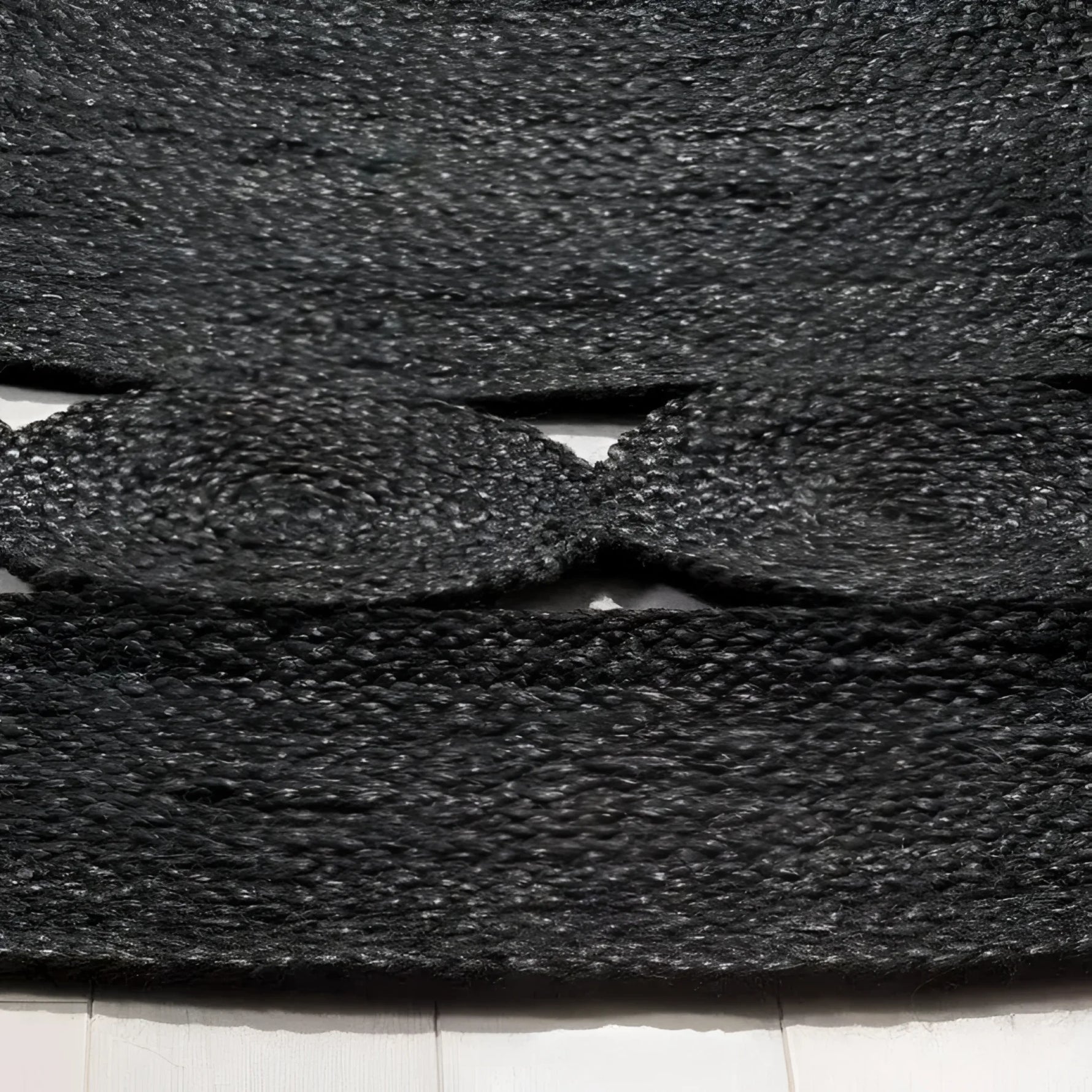 Close-up view of a black round jute area rug, showcasing its intricate woven texture. Perfect for adding a natural touch to any office or living room, this large area rug combines durability with style.