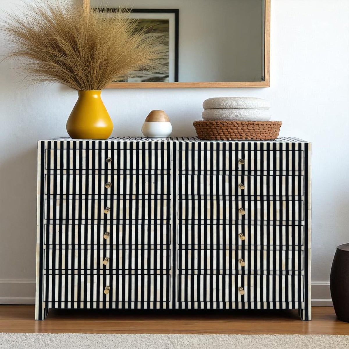 Black and white striped cabinet with decorative items on top against a plain wall.