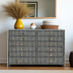 Black and white striped cabinet with decorative items on top against a plain wall.