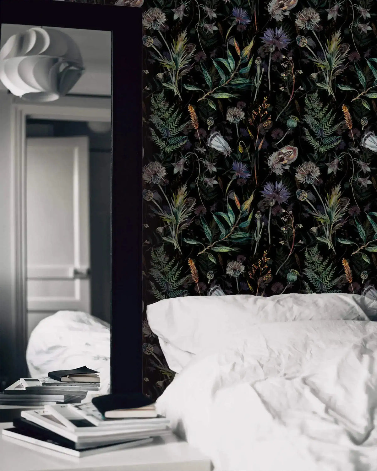 Black wallpaper with thistles, ferns and wildflowers behind white bedding and a tall mirror