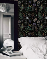 Black wallpaper with thistles, ferns and wildflowers behind white bedding and a tall mirror