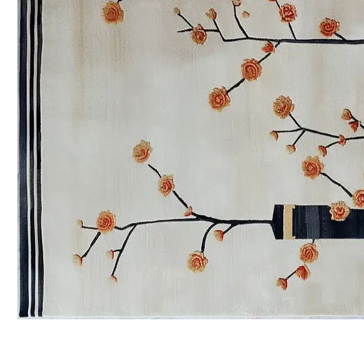 Elegant hand-tufted wool area rug featuring an abstract floral design with delicate orange blossoms on black branches against a soft cream background. Perfect for adding a touch of nature-inspired elegance to any room.