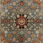 A beautifully detailed hand-knotted area rug featuring intricate Persian-inspired floral patterns in rich shades of red, brown, and beige against a soft gray background. This wool rug is perfect for adding a touch of elegance to living rooms, especially in an 8x10 size, making it a standout piece among area rugs for living rooms.