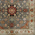 A beautifully intricate Blissful Bouquet Hand Knotted Area Rug showcasing a Persian-inspired design. The rug features ornate floral patterns with rich colors of red, gold, and beige against a gray background, ideal for enhancing any living room space. Perfect as an 8x10 wool rug, this piece is a stunning addition to area rugs for living rooms, offering both elegance and comfort.