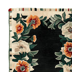 Close-up view of the Bloom Border Hand Tufted Rug, featuring vibrant floral patterns with orange and white blossoms on a dark background. This wool area rug adds a touch of elegance to living room spaces, perfect for those seeking stylish area rugs for their home decor.