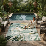 Woman sitting on a decorative rug by a pool with lush greenery around