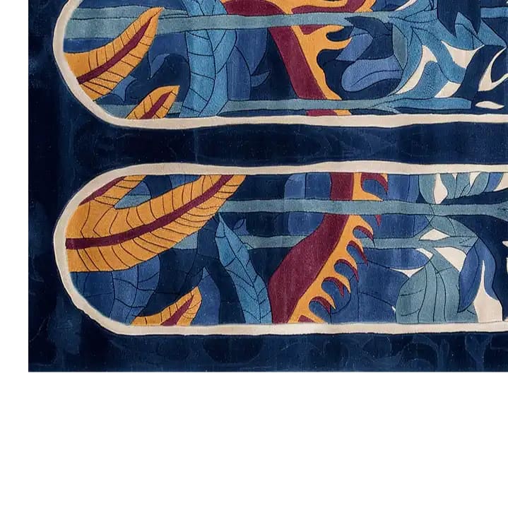 A vibrant area rug featuring a hand-tufted wool design with bold abstract patterns. The image showcases intricate leaf motifs in shades of blue and yellow with accents of red, creating a striking visual contrast on the rug.