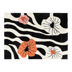 Top view of the Blossom Cascade Hand Tufted Wool Area Rug showcasing a vibrant design with bold black and white zebra stripes, accented by large, colorful abstract floral patterns in shades of orange and pink.