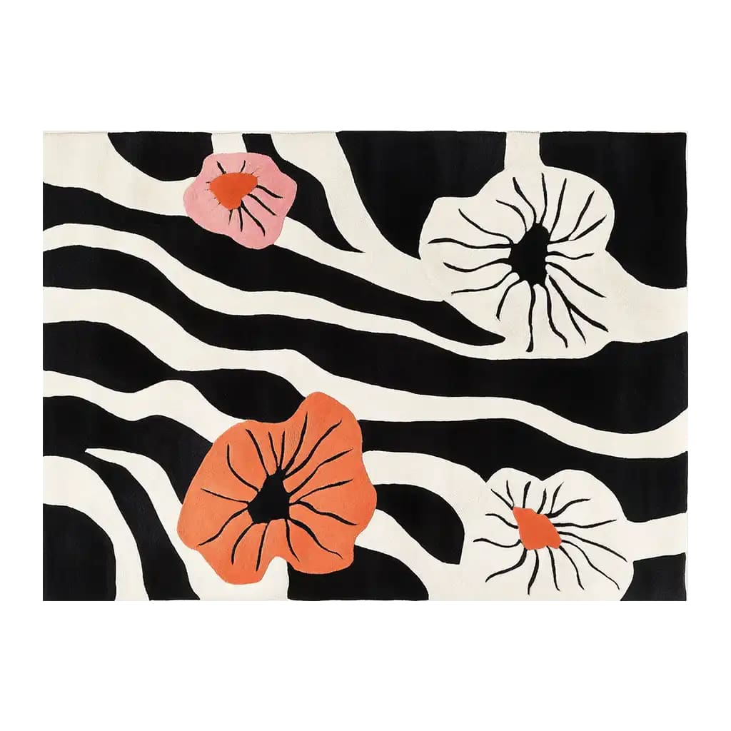 Top view of the Blossom Cascade Hand Tufted Wool Area Rug showcasing a vibrant design with bold black and white zebra stripes, accented by large, colorful abstract floral patterns in shades of orange and pink.